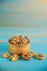 Walnuts on blue rustic table in wooden bowl