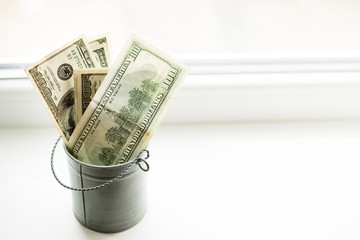 Moneybox, dollars in bucket on white window.light background. place for text. top view. a lot of money