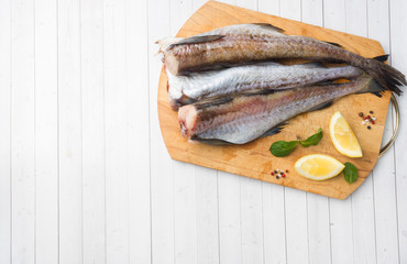 Raw fresh Pollock fish on a wooden Board with lemon Copy space