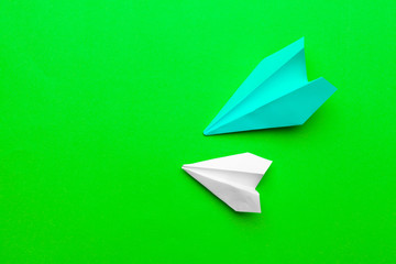 white paper airplane on a green paper background