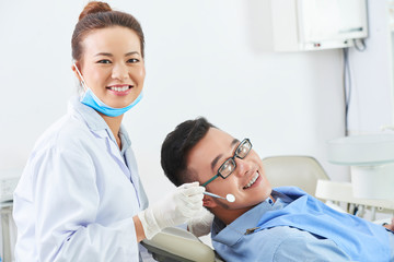 Dentist examining young man's teeth