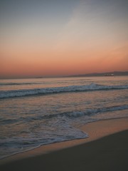 Fototapeta na wymiar Sandy beach in Manhattan beach in Los Angeles at sunrise, beautiful romantic pink sky