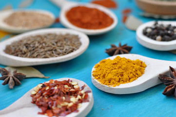 spices in wooden spoons on blue table