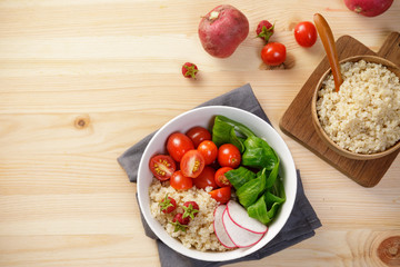 Quinoa salad with vegetables, raspberry and tomatoes on the wooden table. Super food for healthy and concept of balanced diet
