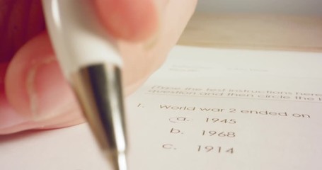 Tracking macro shot of pen marking answers in a history test in school