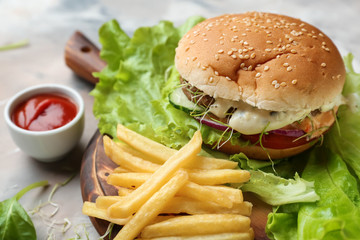 Tasty burger and french fries on table, closeup