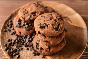 Tasty cookies with chocolate chips on wooden plate, closeup