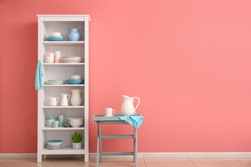 Set of clean dishes on shelves near color wall