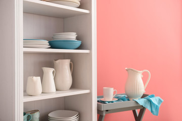 Fototapeta na wymiar Set of clean dishes on shelves near color wall