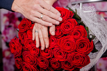 Duży bukiet czerwonych róż i dłonie zakochanej pary - obrazy, fototapety, plakaty