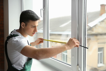 Male worker taking measurements of window in flat