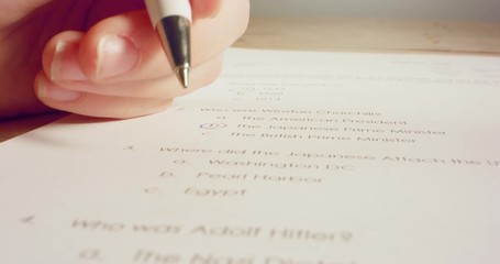 Tracking macro shot of pen marking answers in a history test in school