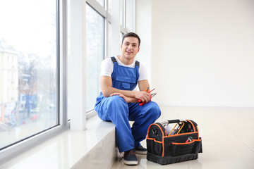 Young worker sitting on window sill in flat