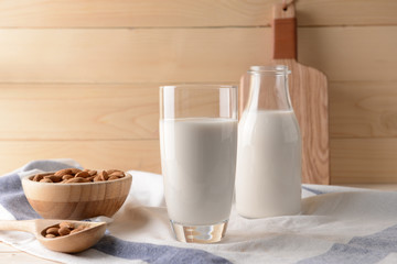 Glass and bottle of healthy almond milk on table