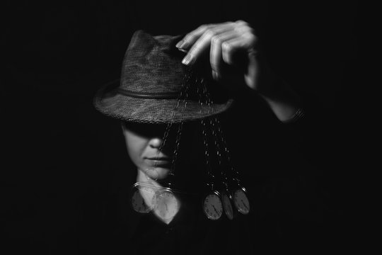 Female hypnotist with swinging pendulum on dark background