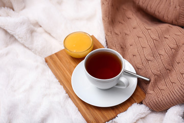 Cup of hot tea and bowl with honey on soft plaid