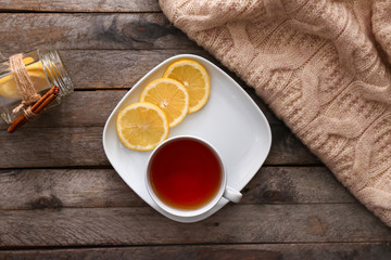 Plate with cup of hot tea and lemon on wooden table