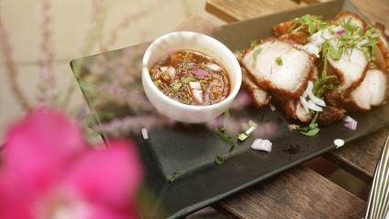 Deep Fried Crispy Pork Belly Cooked with Garlic and spicy dipping sauce on wooden table background.