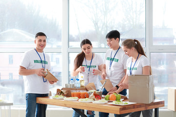 Young volunteers with food for poor people indoors