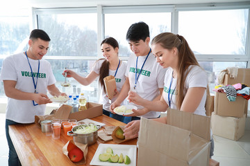 Young volunteers with food for poor people indoors