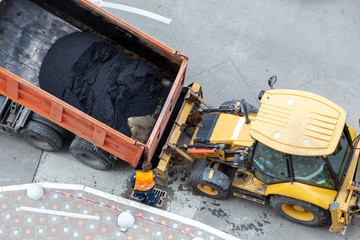 Heavy industrial dump truck unloading hot asphalt .City road construction and renewal site © Kirill Gorlov