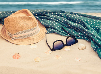 Straw hat, cover-up beachwear wrap and sun glasses on a tropical beach .