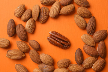 One pecan nut among almond ones on color background. Concept of uniqueness