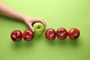 Female hand with tasty apples on color background. Concept of uniqueness