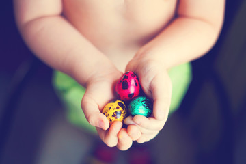 Fototapeta na wymiar Colorful easter eggs in child hands after egg-hunt