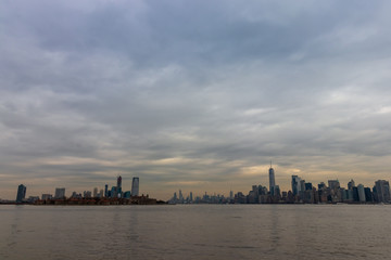 Obraz premium View of New York City skyline with dramatic sky at dusk from Liberty Island, New York, USA