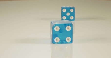 Slow motion macro shot of dice falling and rolling on reflective surface