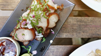 Deep Fried Crispy Pork Belly Cooked with Garlic and spicy dipping sauce on wooden table background.