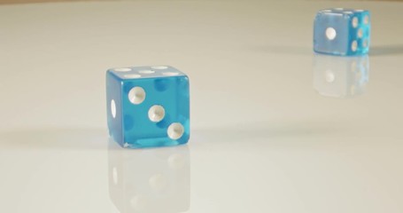 Slow motion macro shot of dice falling and rolling on reflective surface