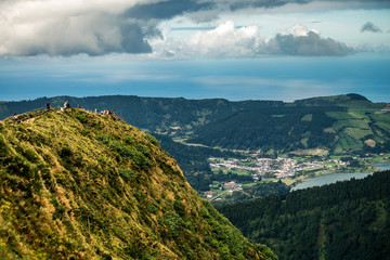 Fototapeta na wymiar Beautiful lansdcape of Azores island, Sao Miguel. You can see the rock on foreground and city on background. Cloudy sky.