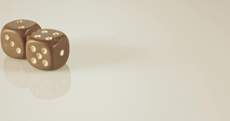 Slow motion macro shot of dice falling and rolling on reflective surface