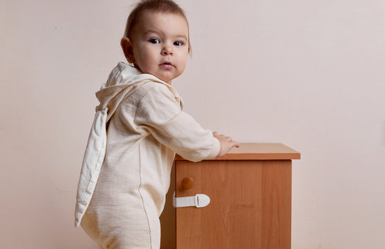 Baby girl trying to open the cabinet with baby proofing lock safe home