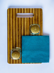 Pepper pot and salt shaker stand empty on a cutting board on a white background