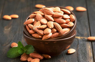 Freash almond in bowl on dark wooden kithcen table background, selective focus
