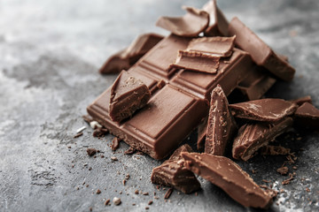 Pieces of tasty milk chocolate on grunge background
