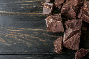 Pieces of tasty dark chocolate on wooden background