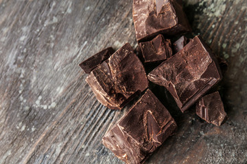 Pieces of tasty dark chocolate on wooden background