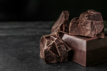 Pieces of tasty chocolate on dark background