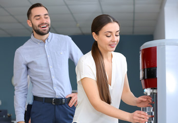 Colleagues drinking water from cooler in office