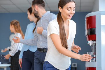 Colleagues drinking water from cooler in office