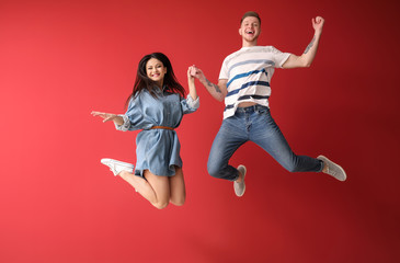 Happy jumping couple against color background