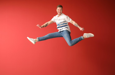 Fototapeta na wymiar Handsome jumping man against color background