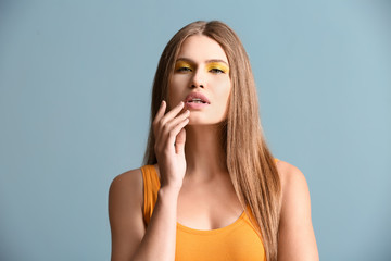 Fototapeta premium Beautiful young woman with bright makeup on color background