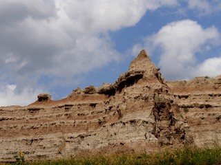 A sharp pinnacle rises above rock formations at the Badlands National Park in South Dakota, USA.