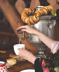 women's hands opened the tap of the samovar and took hot water in a mug of tea