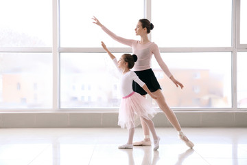 Little ballerina training with coach in dance studio